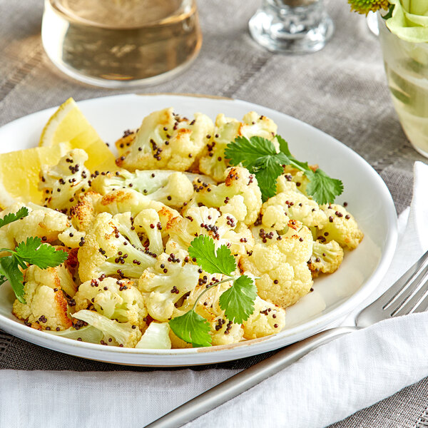 A plate of cauliflower with lemon and parsley on a table.