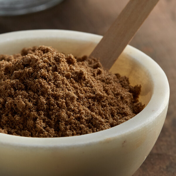 A bowl of brown powder with a wooden spoon.