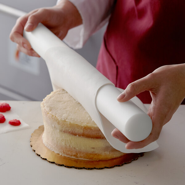 A person using Satin Ice ChocoPan to cover a cake with white chocolate.