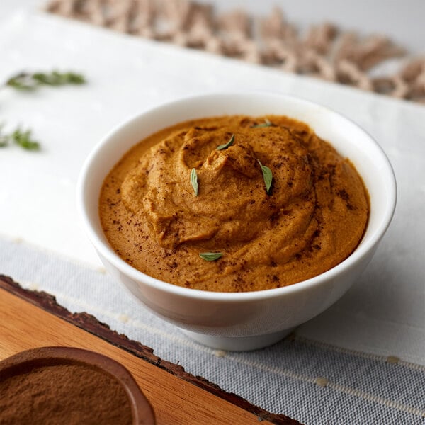 A bowl of brown food with brown liquid and brown powder on a wooden surface.