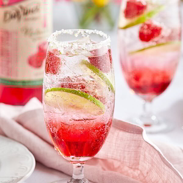A glass of red drink with lime slices and DaVinci Gourmet Pacific Northwest Raspberry syrup.