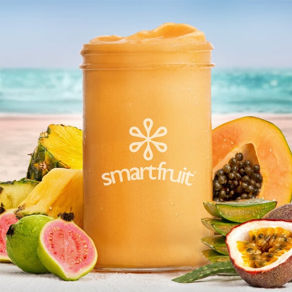 A glass of Smartfruit Tropical Harmony puree with a straw and fruit on the rim.