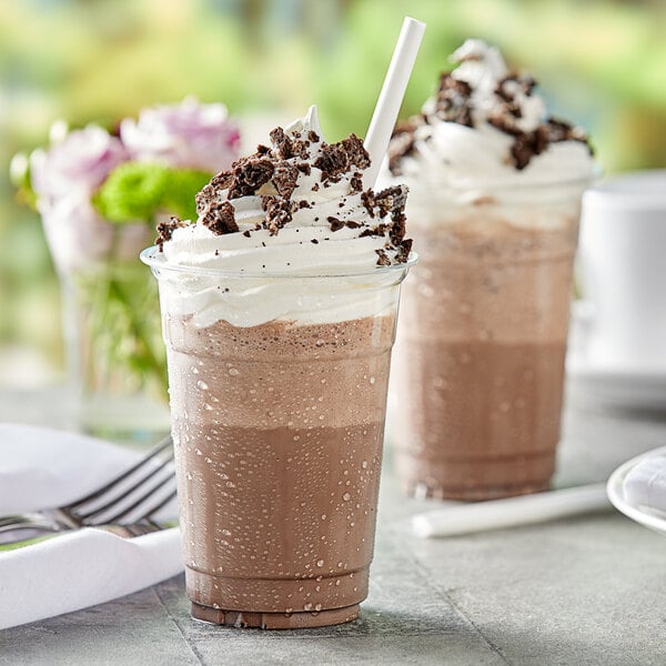 Two cups of Capora Cookies & Cream Frappe topped with whipped cream and cookies.