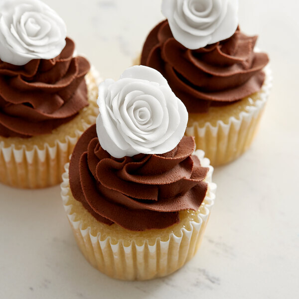 A cupcake with white and brown frosting and a white rose on top.