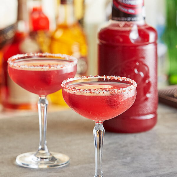 Two glasses of pink raspberry drinks on a table.