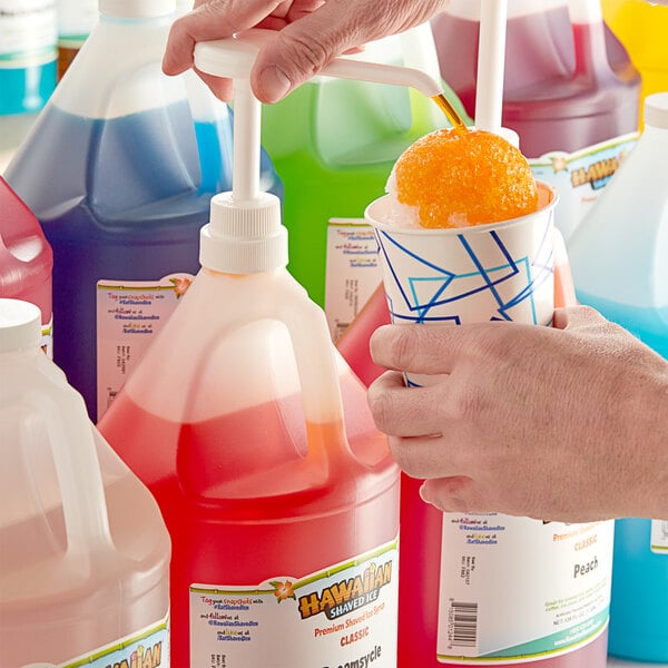 A person pouring Hawaiian Shaved Ice Dreamsycle syrup into a cup.