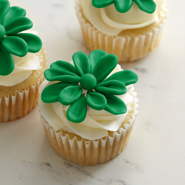 A close up of a cupcake with green ChocoPan modeling chocolate flowers on top.