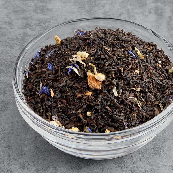 A bowl of Twinings Lady Grey loose leaf tea with blue and orange flowers.