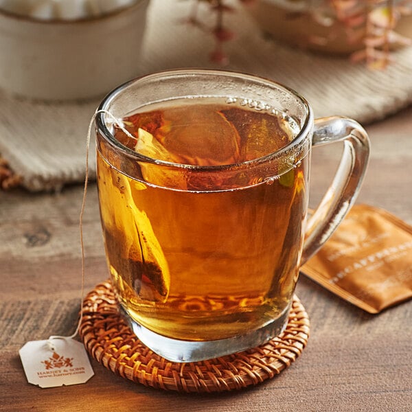 A glass mug of Harney & Sons Decaf Ceylon Tea with a tea bag in it on a coaster.