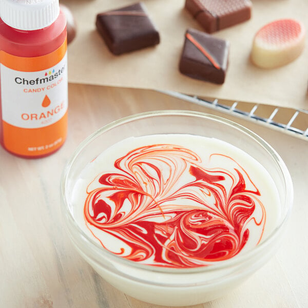 A bowl of white liquid with orange swirls on top of it.