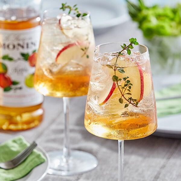 A glass of Monin apple-flavored liquid with a slice of apple and a garnish.