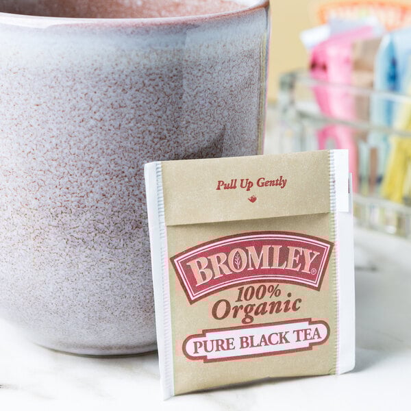 A cup of tea with a packet of Bromley Organic Black Tea.