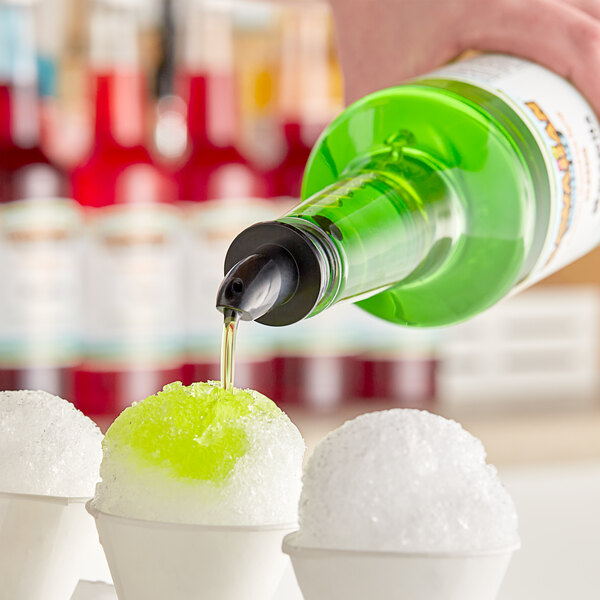 A person pouring Hawaiian Shaved Ice Margarita syrup onto a snow cone.