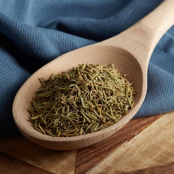 A wooden spoon filled with Regal rosemary leaves.
