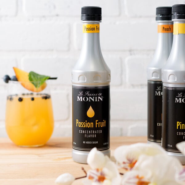 Three bottles of Monin passion fruit concentrated flavor on a table.