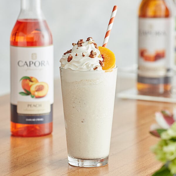 A glass of milkshake with Capora peach flavoring syrup, whipped cream, and peaches.