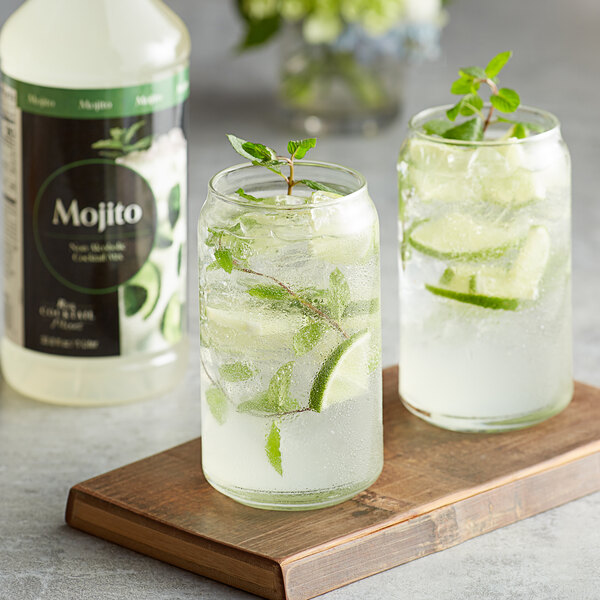 Two glass jars of Regal Cocktail Mojito Mix with a lime and mint garnish next to a bottle of the mix.