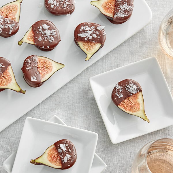 A plate of figs with chocolate and salt on top on a white background.