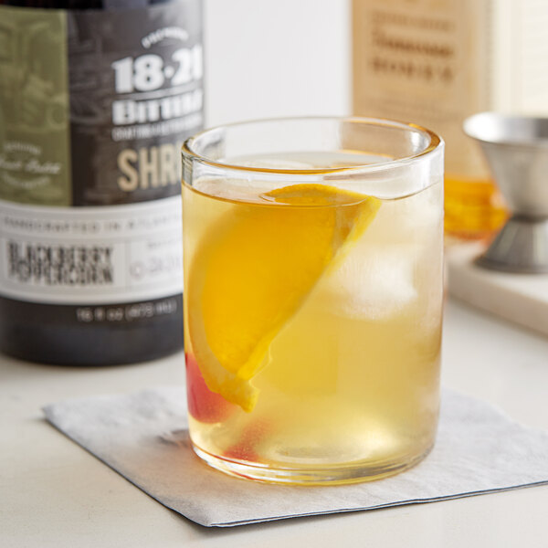 A glass of 18.21 Blackberry Peppercorn Shrub with a slice of lemon in it.