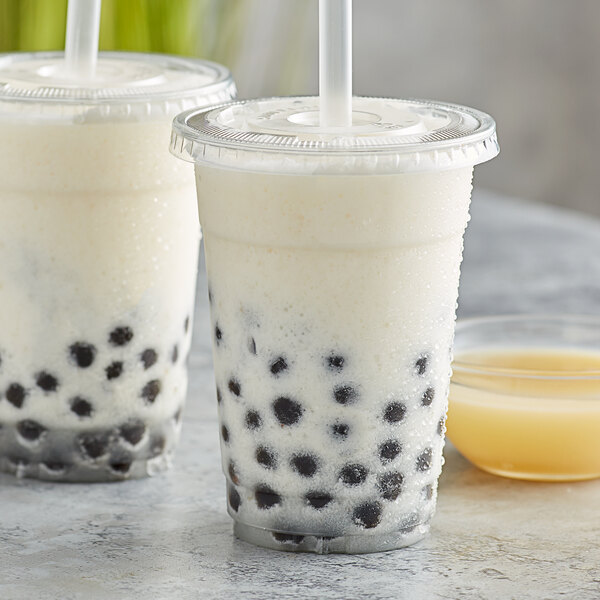 Two plastic cups of Bossen bubble tea with black balls and a straw.