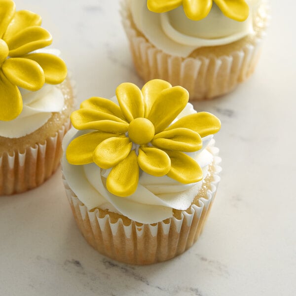 A close up of a cupcake with Satin Ice ChocoPan yellow modeling chocolate on top and a yellow flower.