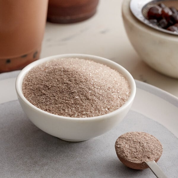 A bowl of brown powder with a spoon.