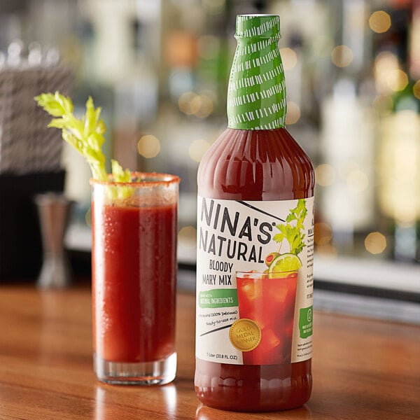 A bottle of Nina's Natural Bloody Mary Mix next to a glass of red liquid.