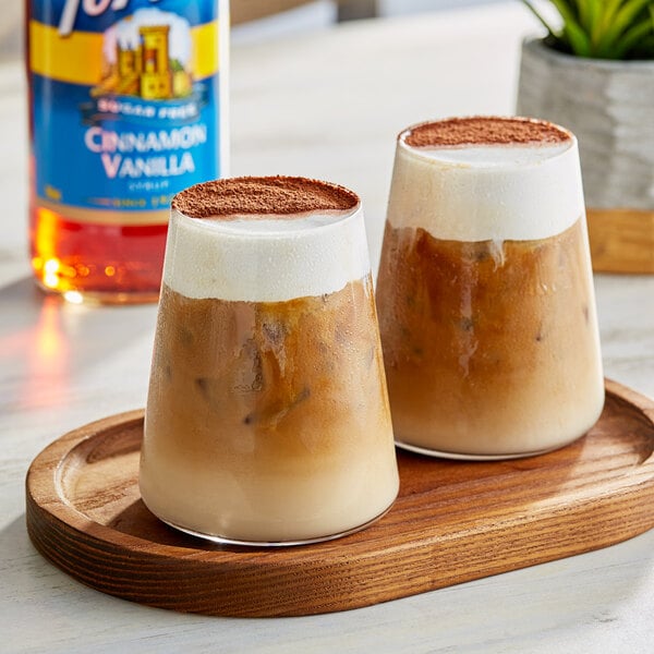 Two glasses of coffee with Torani Sugar-Free Cinnamon Vanilla flavoring on a wooden tray.