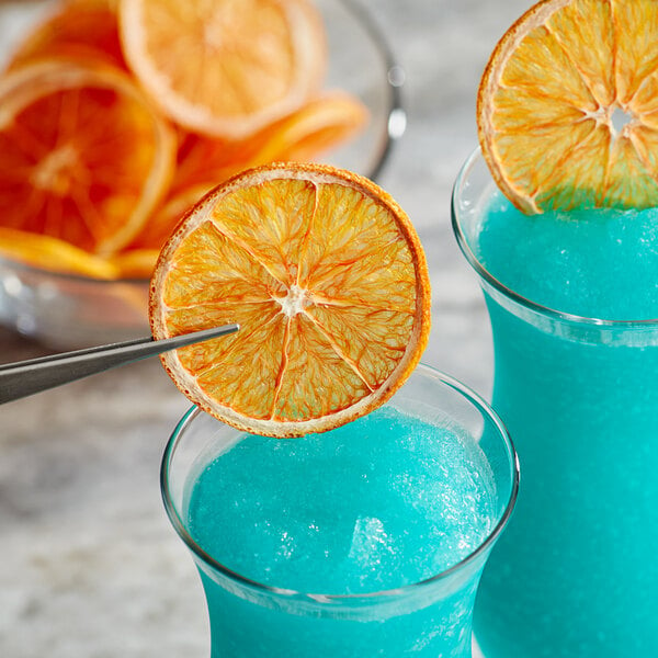 A blue cocktail with a dried Cara Cara orange slice on the rim.