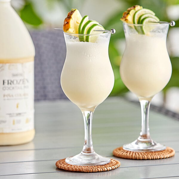 Two glasses of Narvon Pina Colada with pineapple and lime garnish.