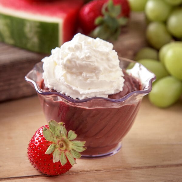 A clear Carlisle tulip dessert dish filled with chocolate pudding topped with whipped cream and strawberries.