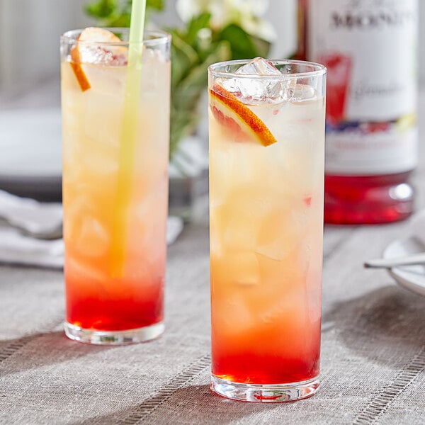 Two glasses of liquid, one red and one orange, on a table.