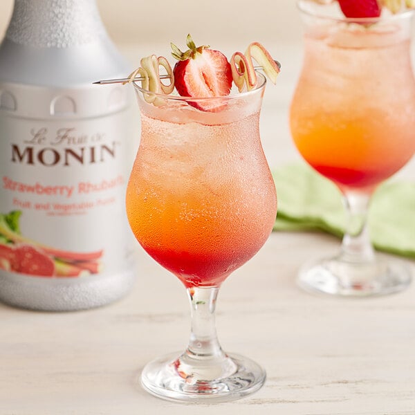 Two glasses of fruity drinks with red and pink straws in them, next to a jar of Monin Strawberry Rhubarb Puree.