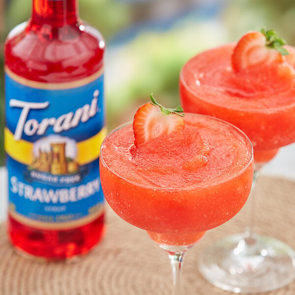 A glass of strawberry flavored drink with a strawberry on the rim.