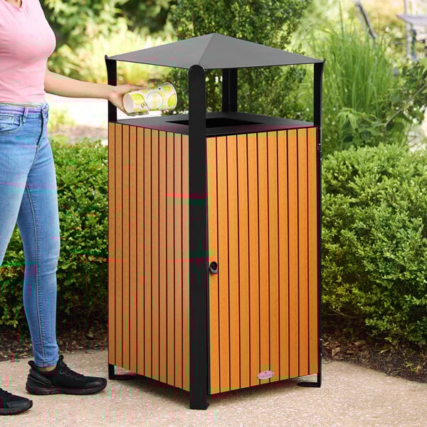 A square outdoor trash can with a covered top, made of steel and wood composite slats.