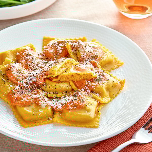 A plate of Seviroli Butternut Squash Square Ravioli with sauce and a fork.