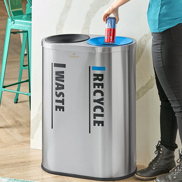 A stainless steel indoor trash can with separate waste and recycle compartments.
