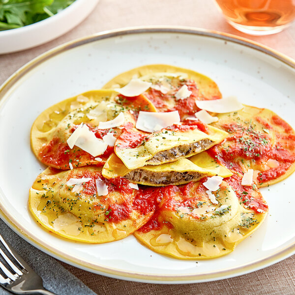 A plate of Seviroli Porcini and Truffle Round Ravioli with sauce and parmesan.