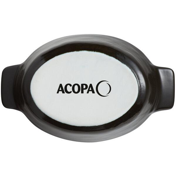 An oval white porcelain dish with black text reading "Acopa Keystone" on it.