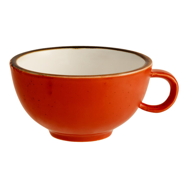 A porcelain cup with an orange exterior and white interior.