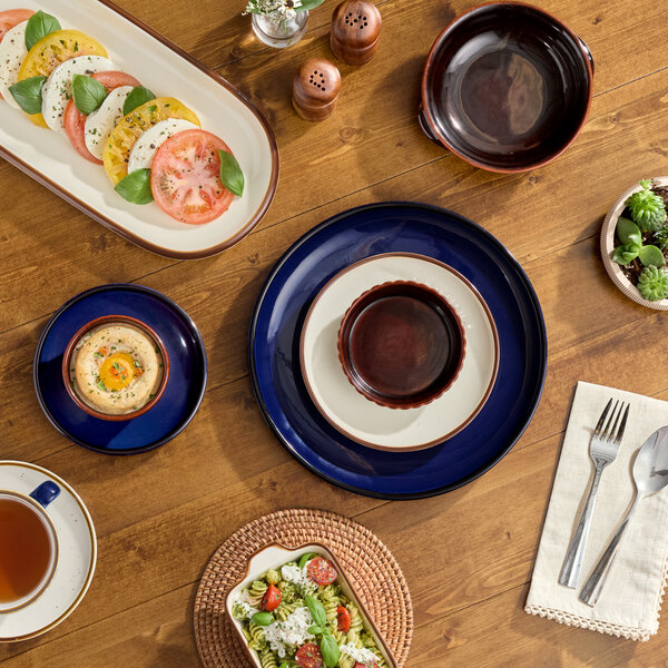A table with Acopa Keystone Azora Blue Porcelain Coupe Plates and food on it.