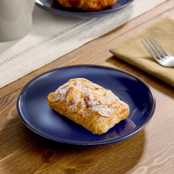 A rectangular almond pastry is served on a blue porcelain coupe plate.