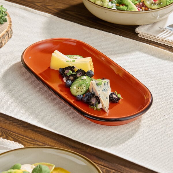An Acopa Sedona Orange porcelain oblong coupe platter on a table with food.