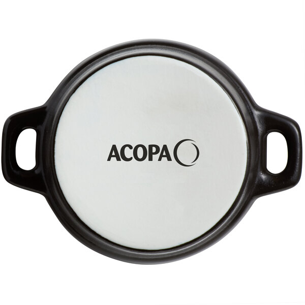 A white porcelain Acopa mini casserole dish with black handles and a lid.