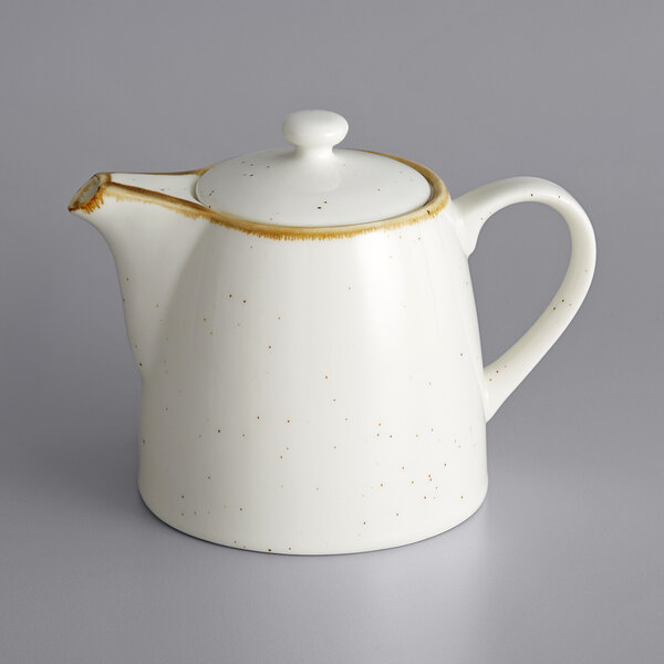 A white teapot with a brown speckled design and a lid.