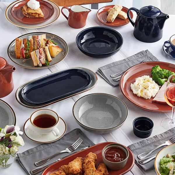 An Acopa Sedona Orange porcelain oblong coupe platter on a table with food on it.