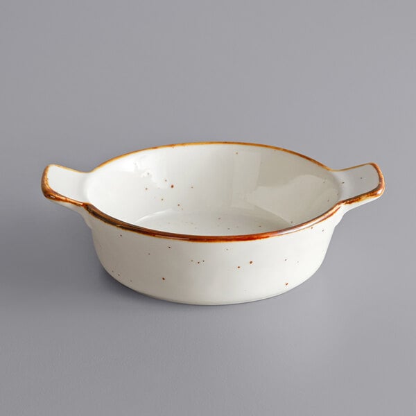A white porcelain casserole dish with brown speckled rim.