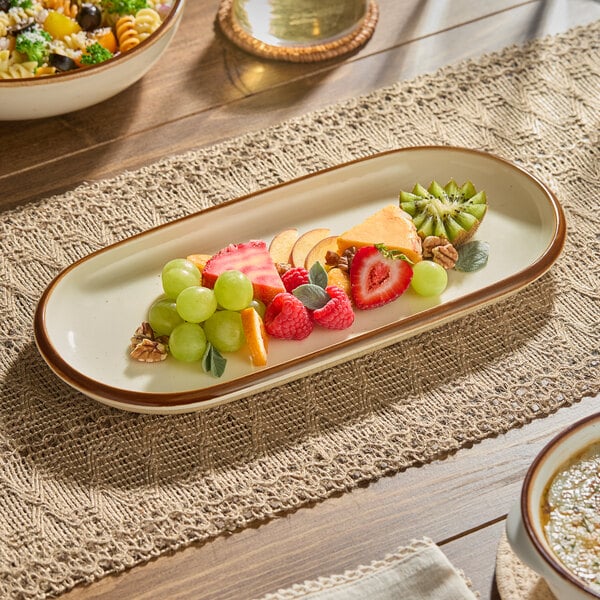 An oblong porcelain platter with a vanilla bean finish, featuring an assortment of fresh fruit and nuts.