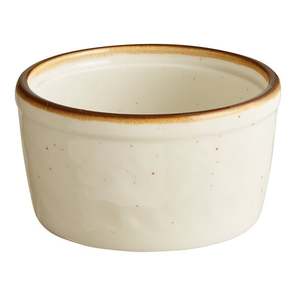 A white porcelain ramekin with brown specks on the rim.