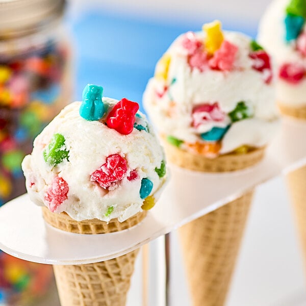 A scoop of ice cream in a waffle cone topped with Albanese gummi bear cubs.